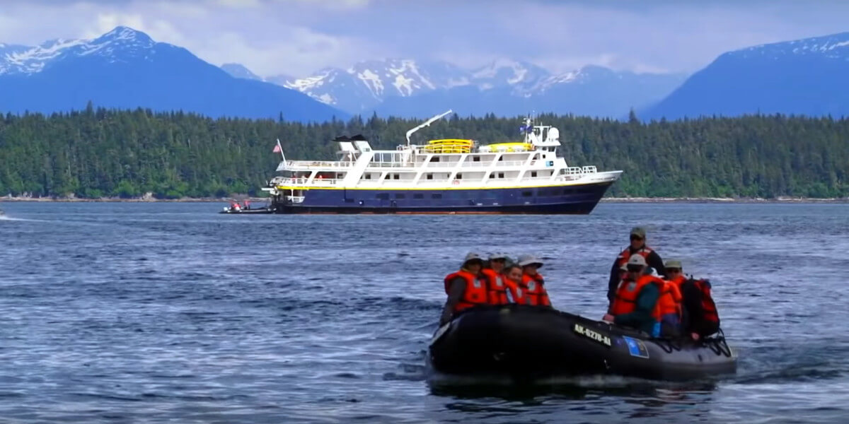 A zodiac with cruise guests explores the Alaska coastline