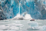 Zodiac with cruise guests experiencing a calving glacier upclose